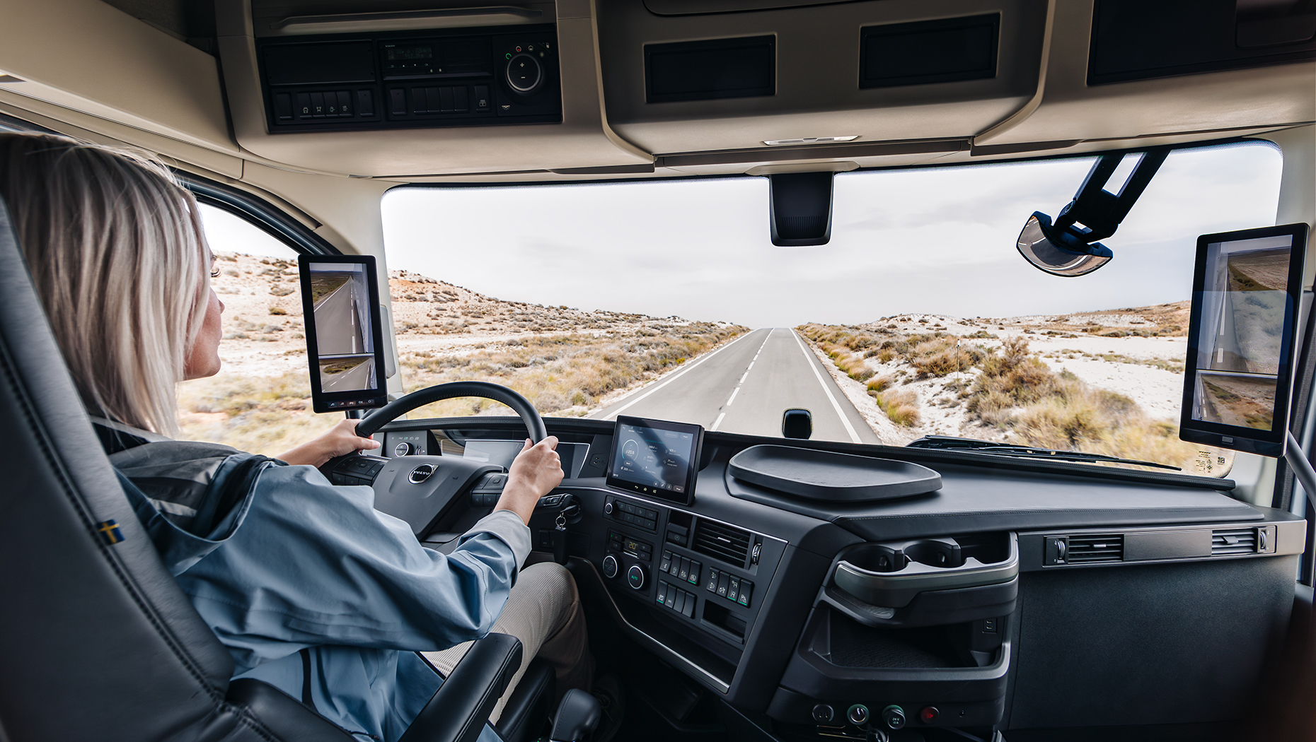 Woman in the driver seat of a Volvo Truck showing the interior of the cabin looking out onto the open road
